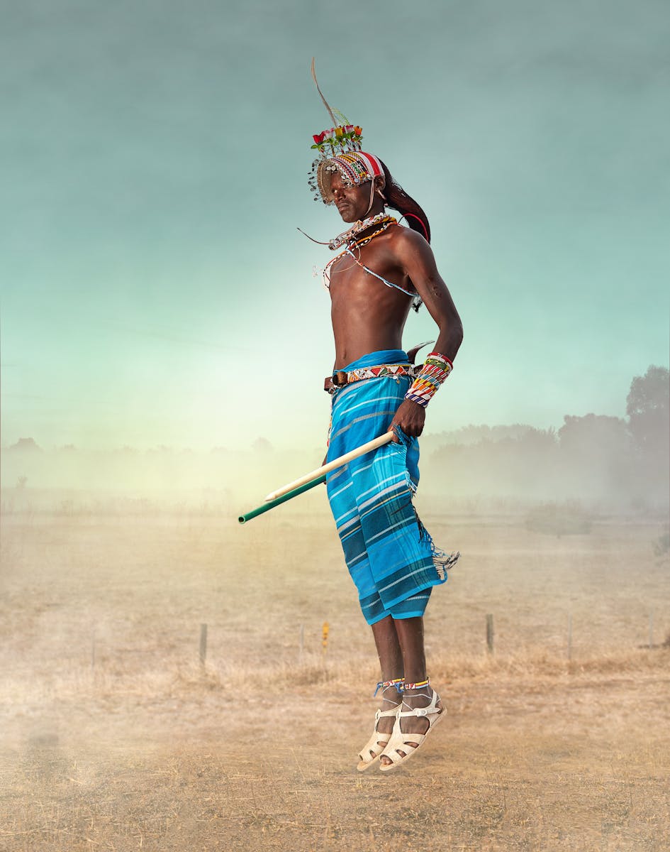 A Maasai warrior in traditional attire jumps high, showcasing cultural dance in Kenya.